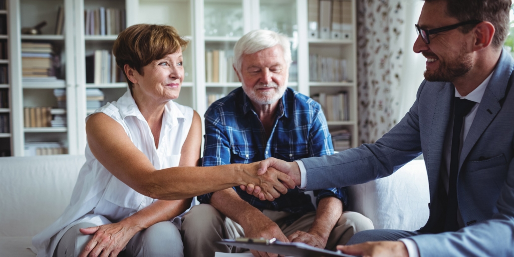 Financial advisor shaking hands with senior woman in living room